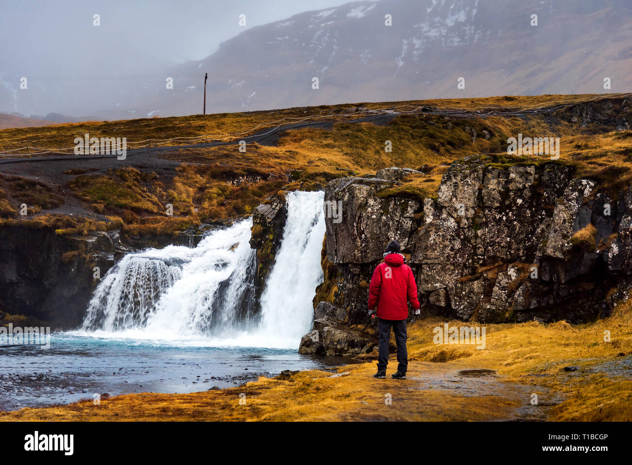 Viaggiatore in famosa cascata Kirkjufellsfoss in Islanda Foto Stock