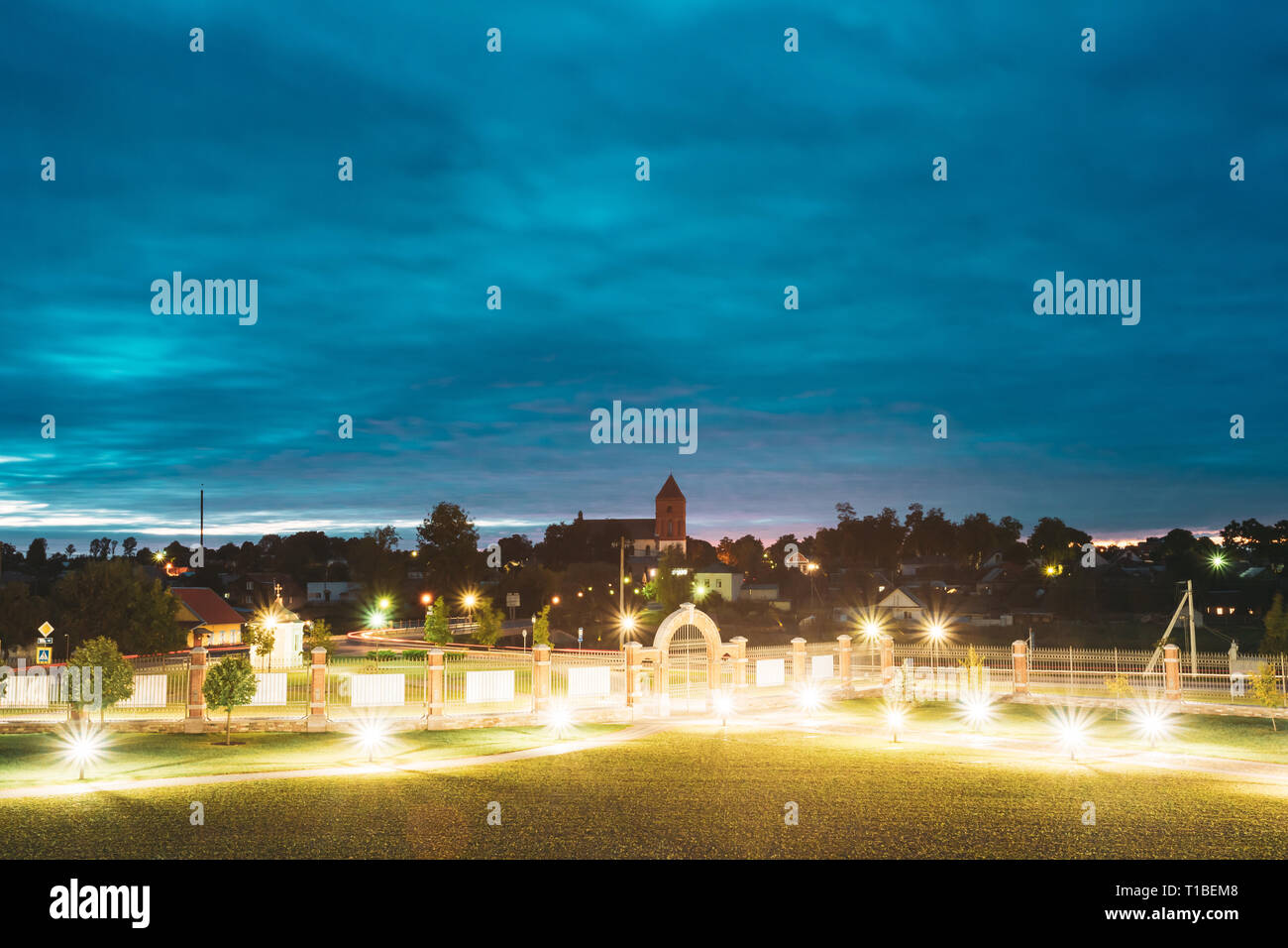 Mir, Bielorussia. Parco vicino complesso del Castello di Mir in serata luci di illuminazione. Famoso punto di riferimento, antico monumento gotico del feudalesimo sotto la notte blu Sk Foto Stock