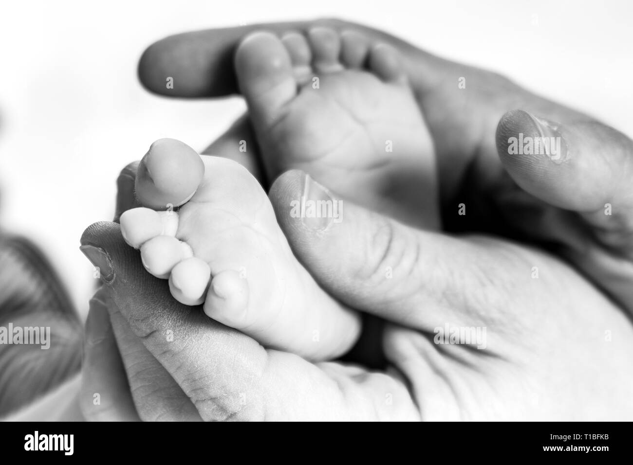 Papà mani tenendo il figlio suo piedi Foto Stock