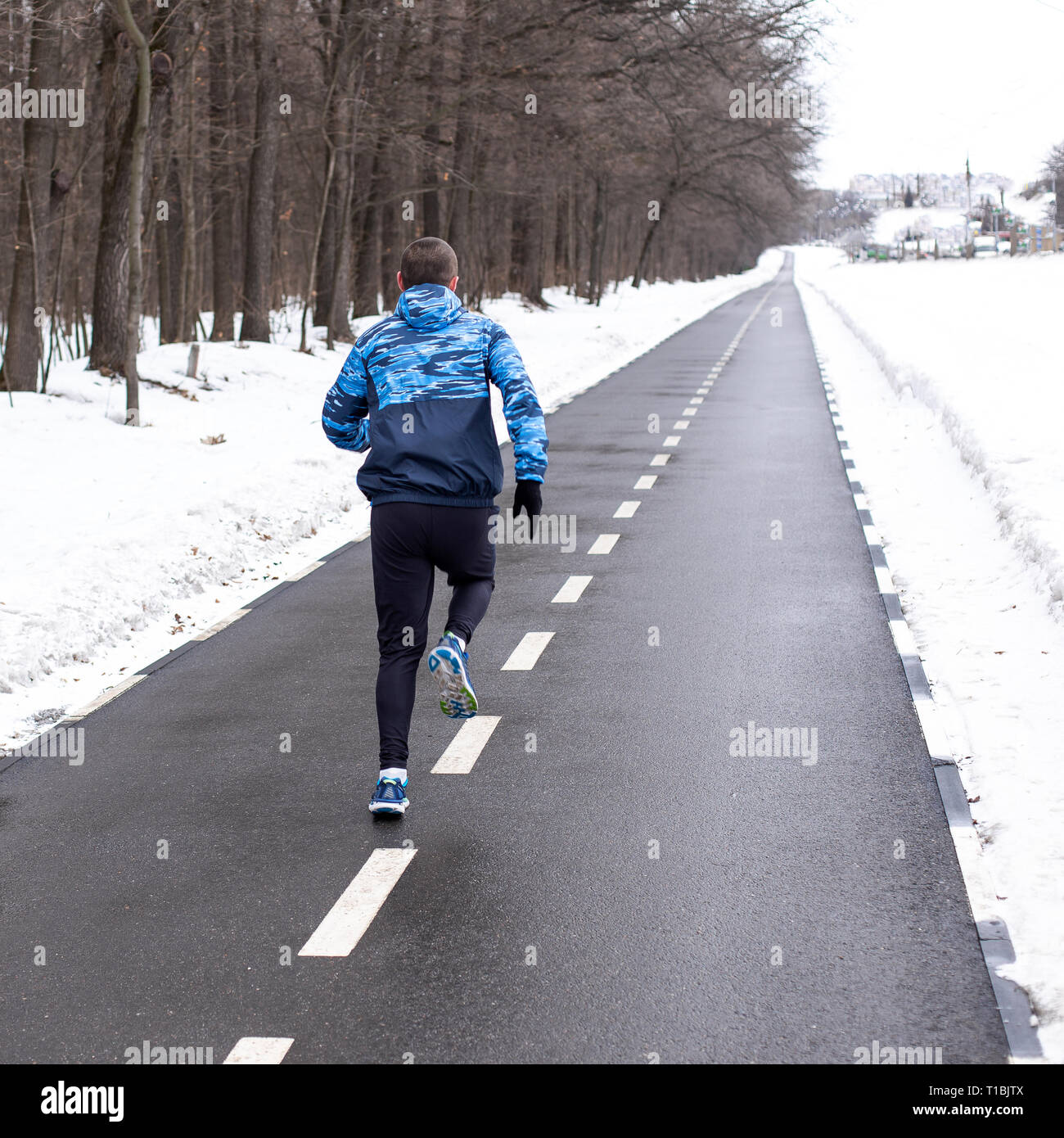 L'uomo runner acceso sulla via in inverno Foto Stock