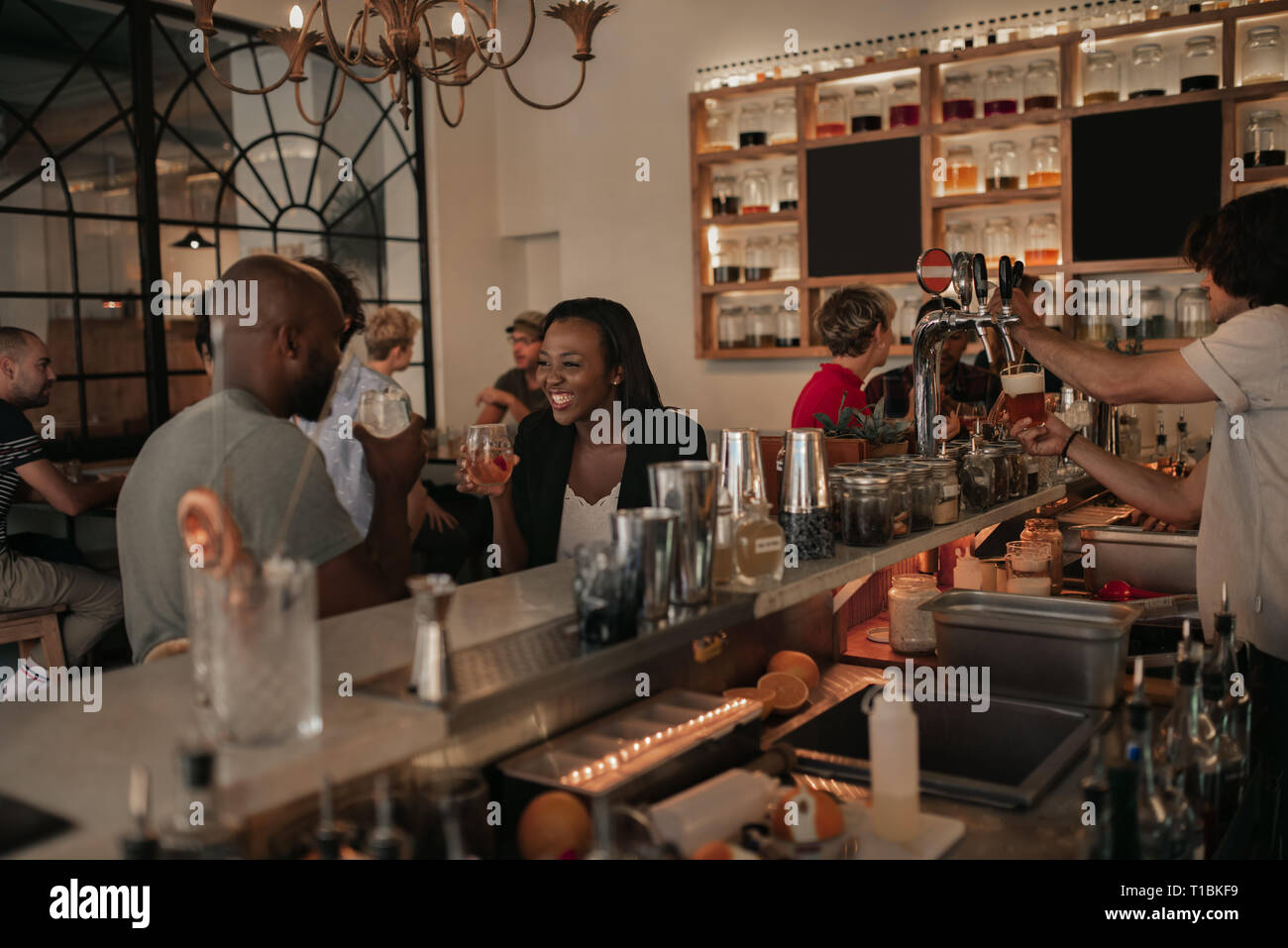 Giovane americano africano giovane parlando con un drink in un bar Foto Stock