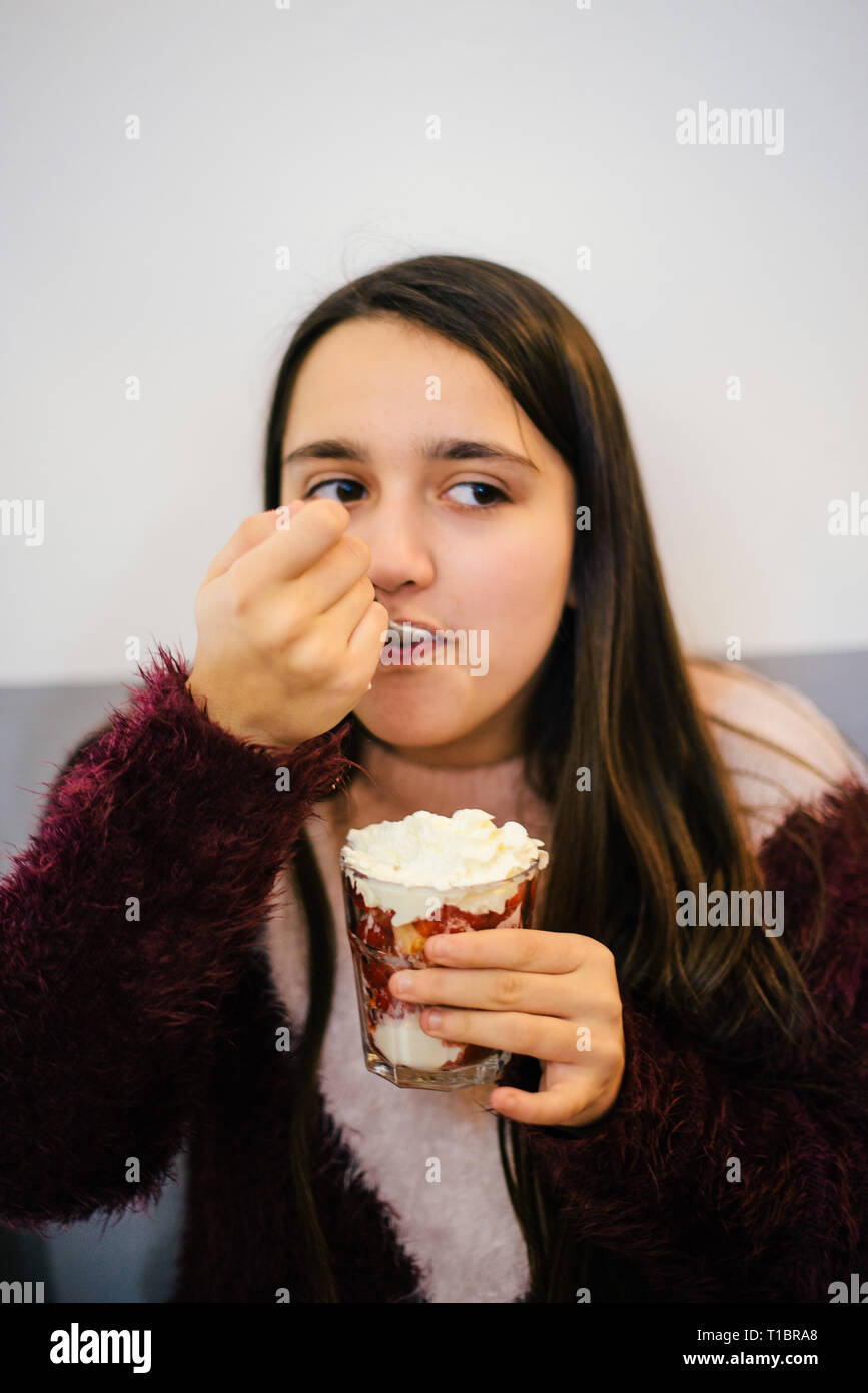 Teen ager ragazza di mangiare un gelato con fragole e panna - ragazza felice di mangiare il dessert - ragazza ritratti Foto Stock