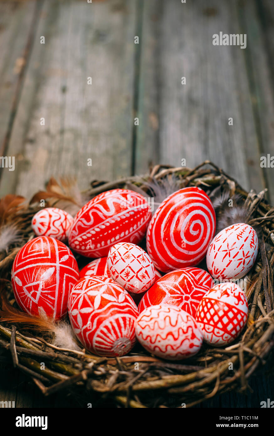 Pasqua uova rosso con folk modello bianco all'interno del Bird Nest su legno rustico sfondo. Tradizionale ucraino uova e pisanka krashanka Foto Stock