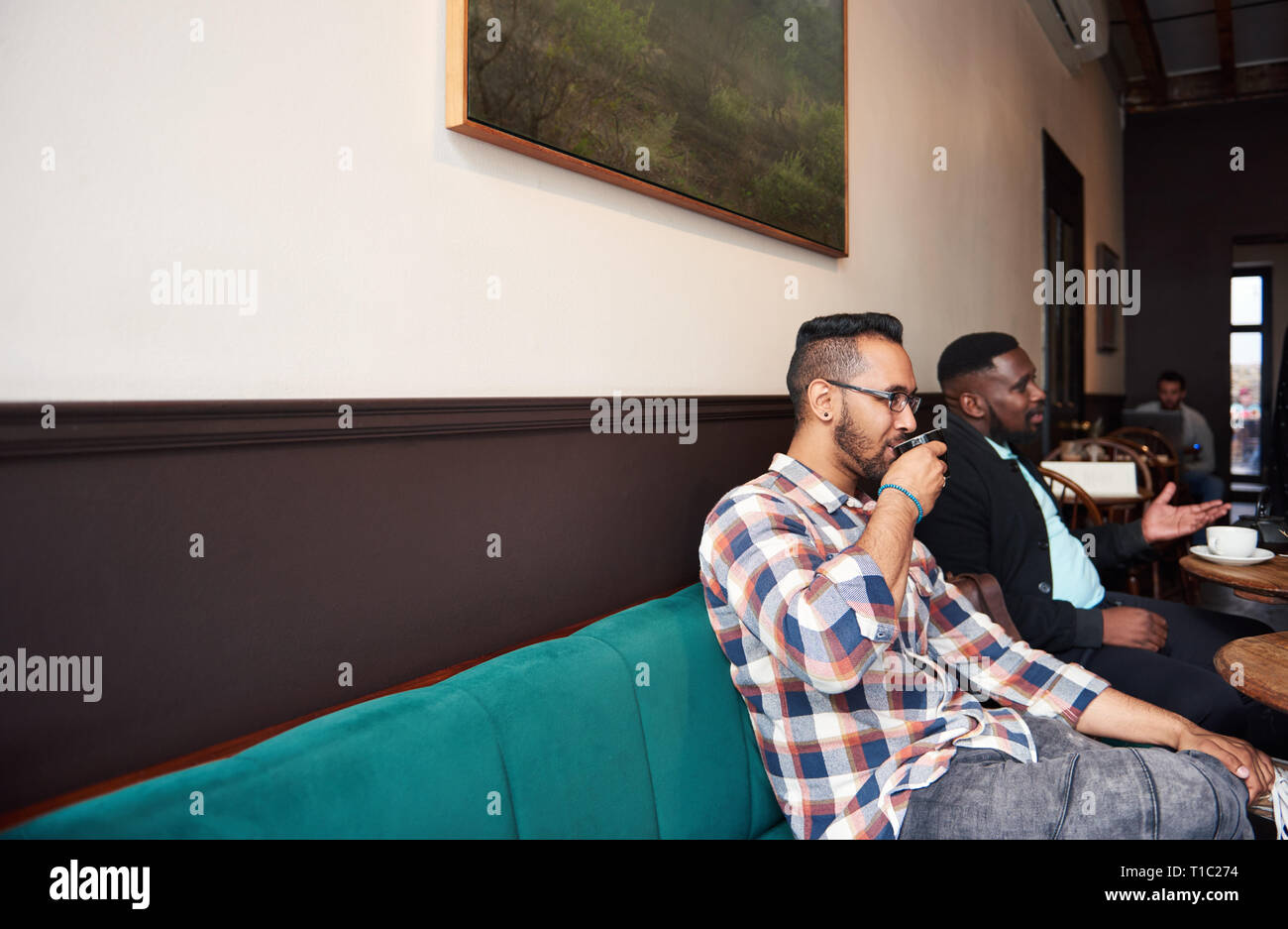 Due uomini con caffè con gli amici in un bar alla moda Foto Stock