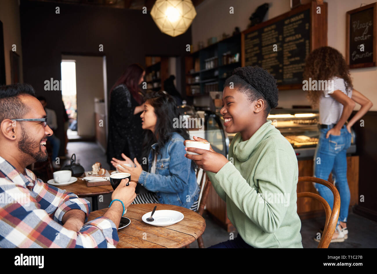 Sorridente giovani amici parlare insieme in un caffè in un bar Foto Stock
