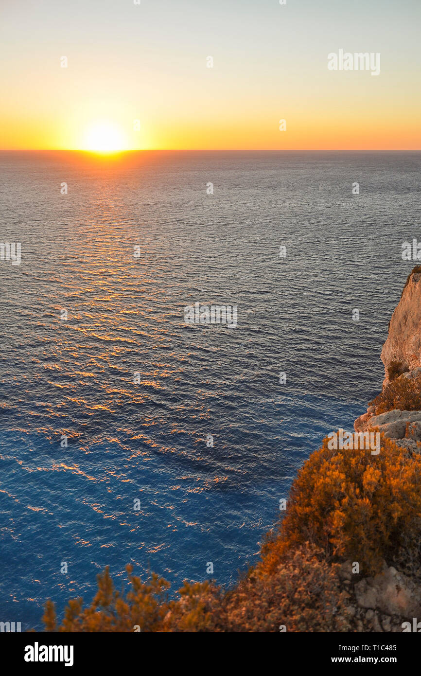 Meravigliosa vista dalla scogliera sul tramonto sull'orizzonte di cristallo, mare blu. Vacanza colorato paesaggio con acqua turchese e rock costa. Foto Stock