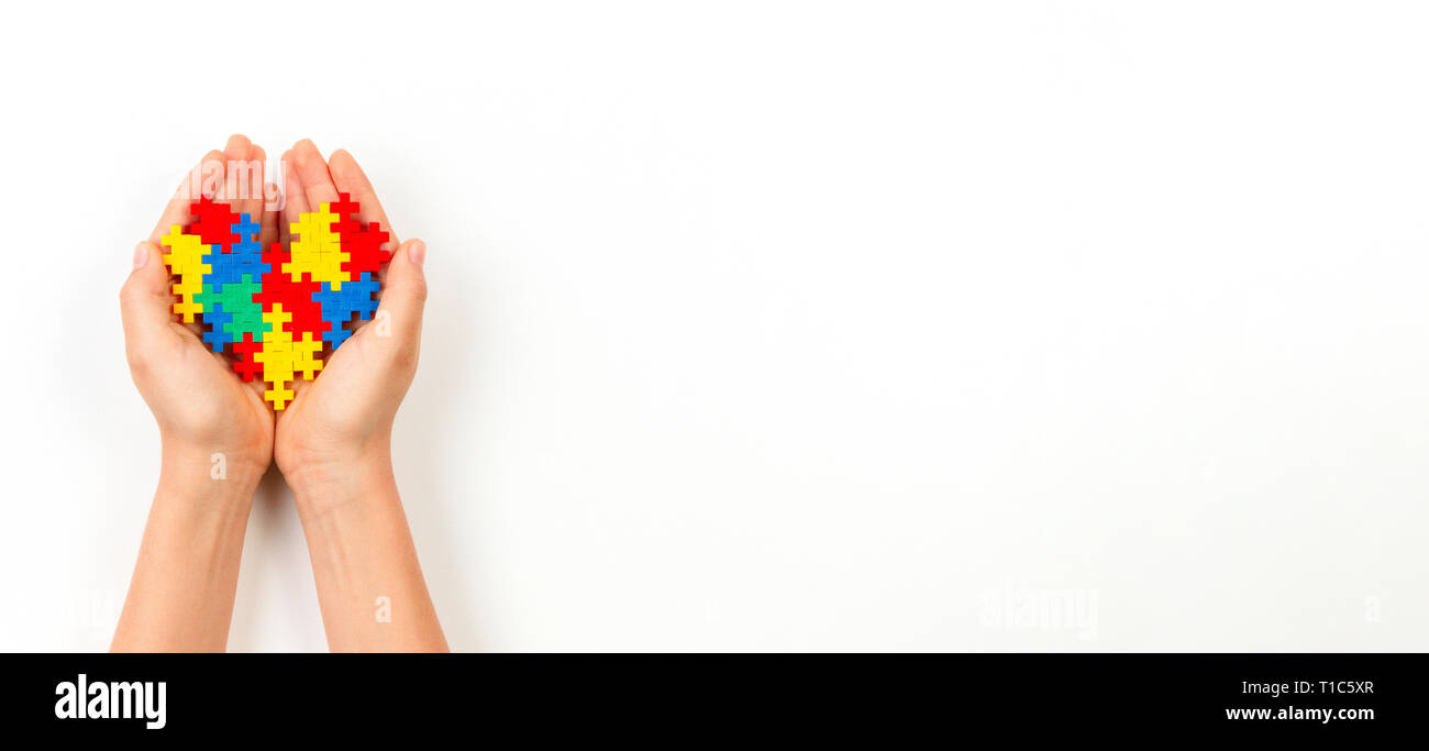 Bambino mano azienda cuore colorato su sfondo bianco. Mondo autismo consapevolezza giorno di concetto Foto Stock