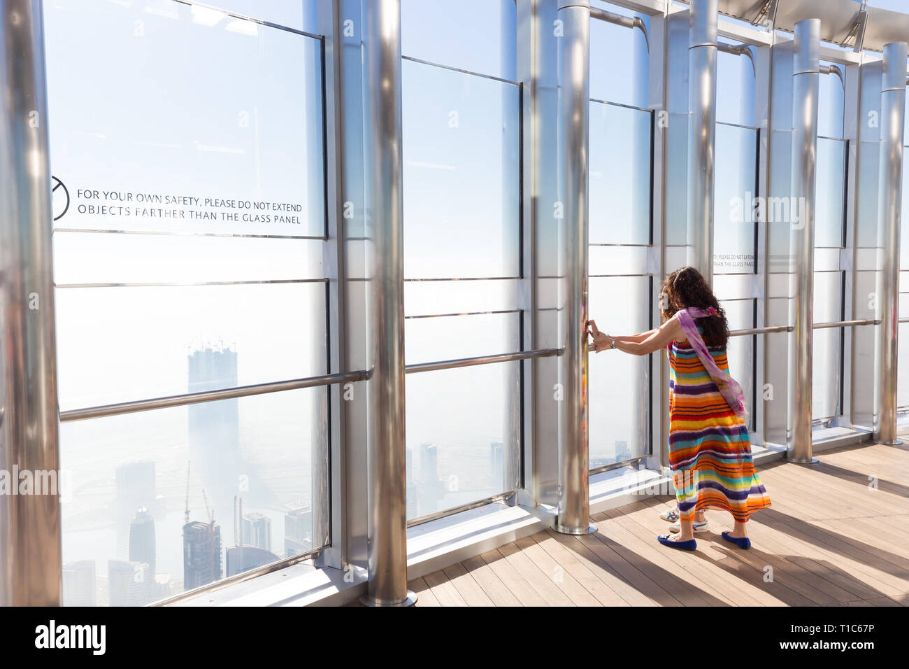 Turisti femmina avente la paura di heigh in alto la piattaforma di osservazione dell'edificio più alto in tutto il mondo,Burj Khalifa a Dubai, EAU. Foto Stock