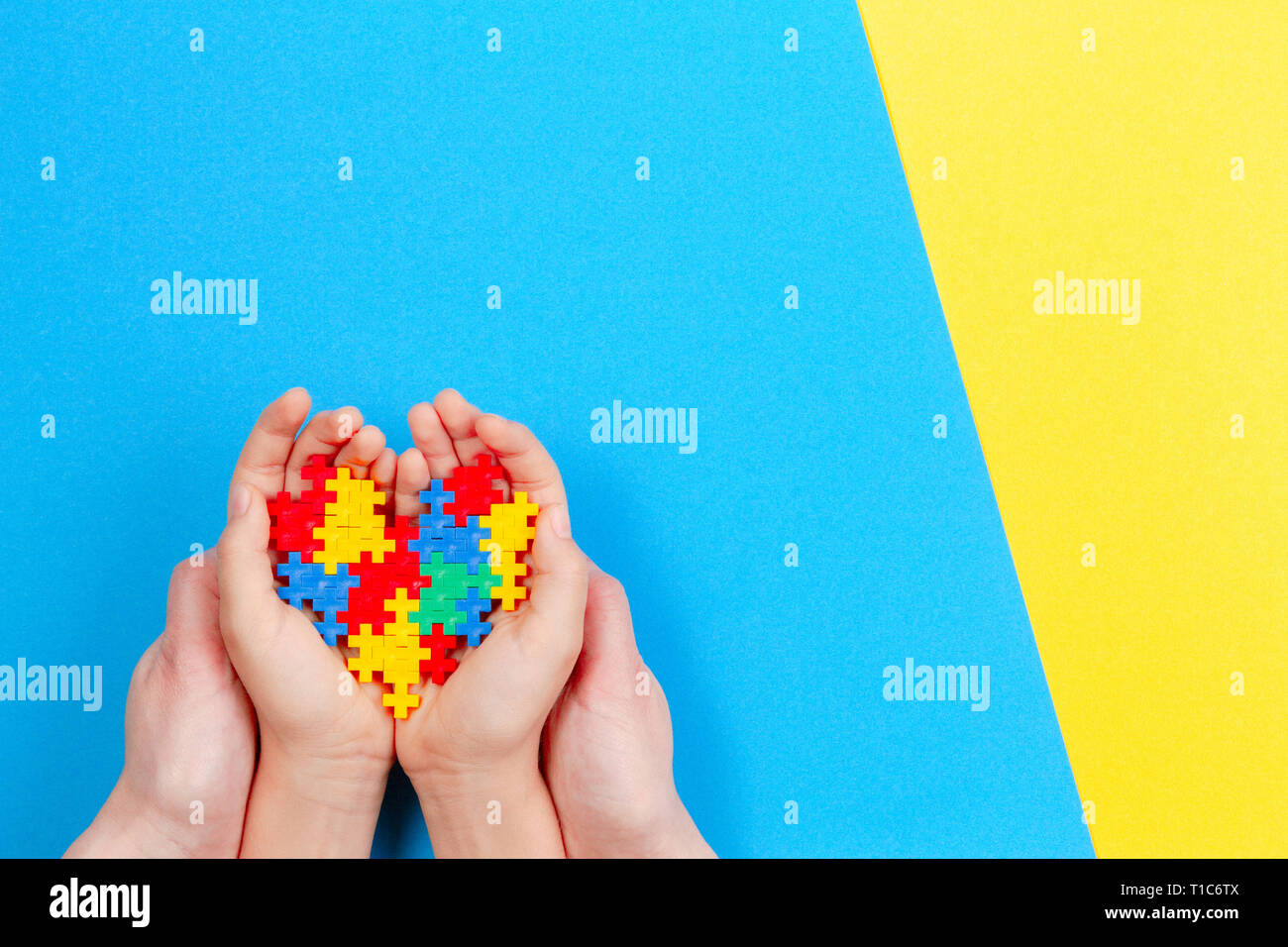 Adulto e bambino mani cuore colorati in giallo e blu sullo sfondo. Mondo autismo consapevolezza giorno di concetto Foto Stock