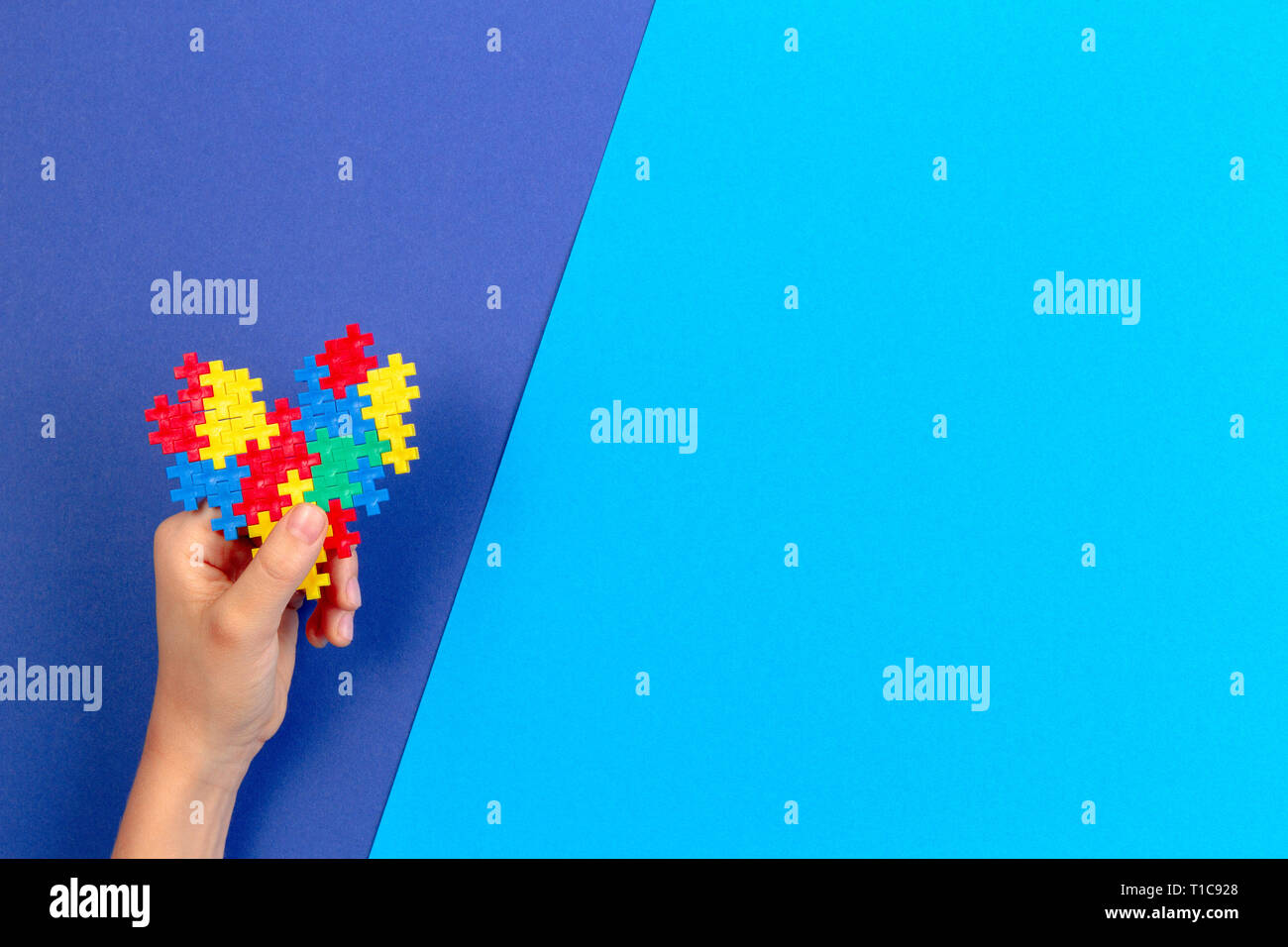 Kid mano azienda cuore colorati su sfondo blu. Mondo autismo consapevolezza giorno di concetto Foto Stock