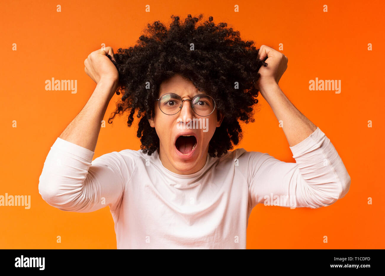 Emotional uomo nero nella disperazione tirando fuori i suoi capelli Foto Stock
