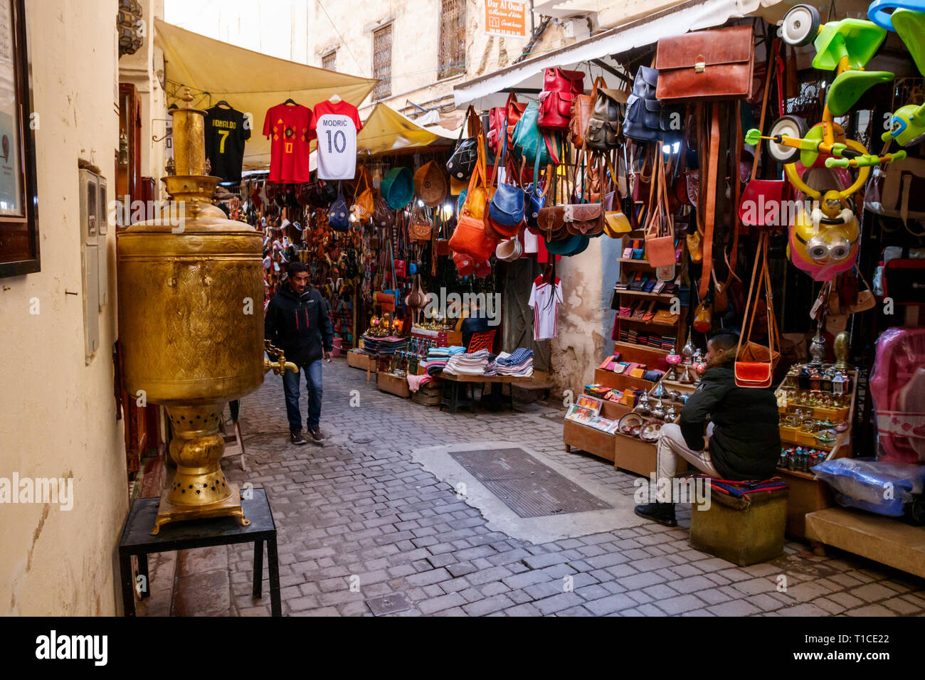 Strada stretta nella medina di Fez con negozi di souvenir e venditori. Fez, in Marocco. Foto Stock