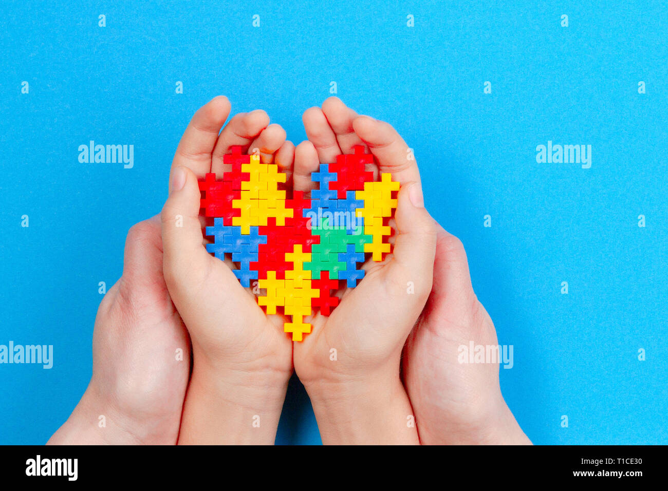 Adulto e bambino mani cuore colorati su sfondo blu. Mondo autismo consapevolezza giorno di concetto Foto Stock