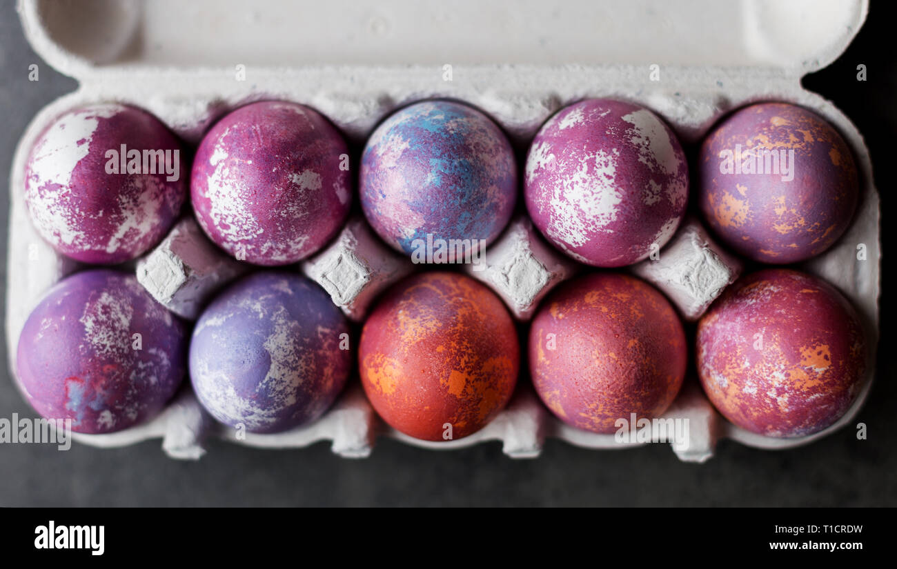 Colorate le uova di pasqua in una scatola di cartone su sfondo scuro. Concetto di sfondo di Pasqua Foto Stock