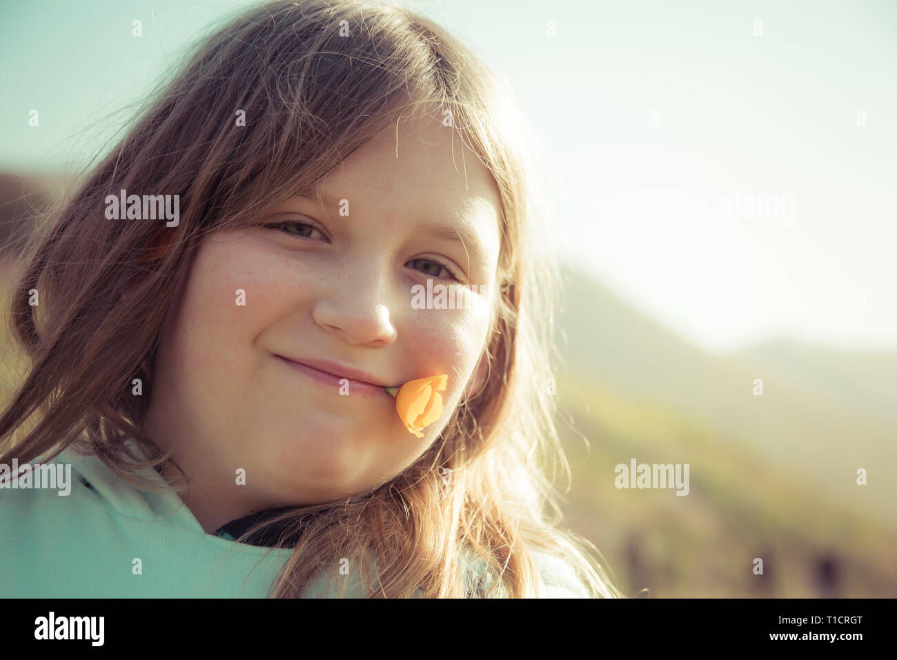 Una ragazza detiene un papavero dorato nella sua bocca tra i fiori selvaggi super bloom nel lago Elsinore, California primavera 2019 Foto Stock