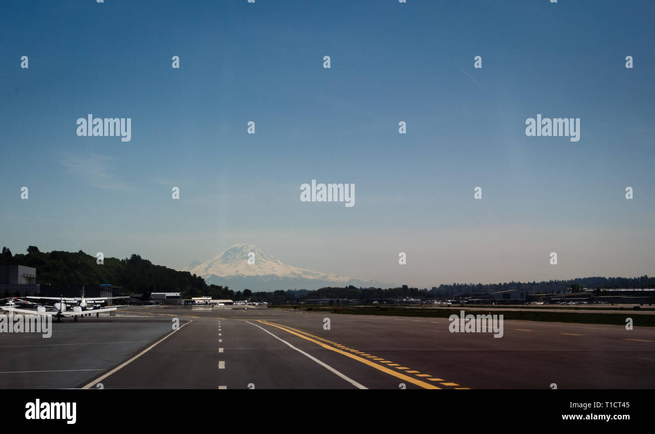 Aeroplano schierate sulla pista di decollo con montagne innevate dritto Foto Stock