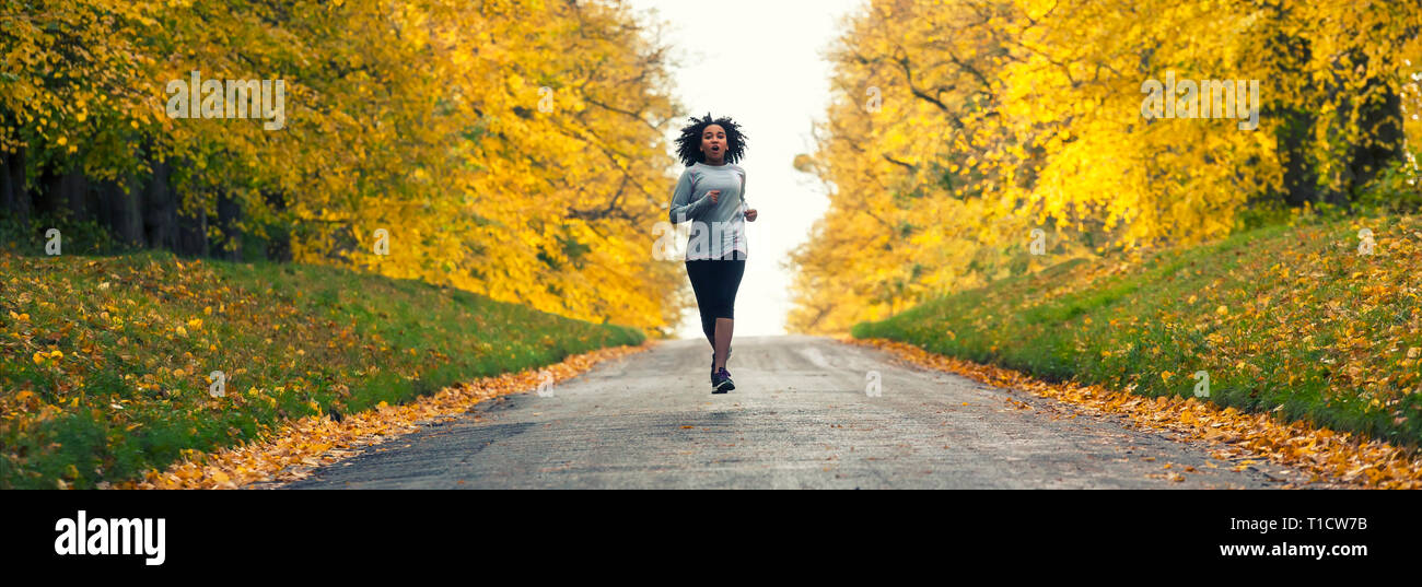 Panoramica banner web splendida razza mista americano africano donna giovane ragazza adolescente in esecuzione fitness jogging in autunno cadono alberi Foto Stock
