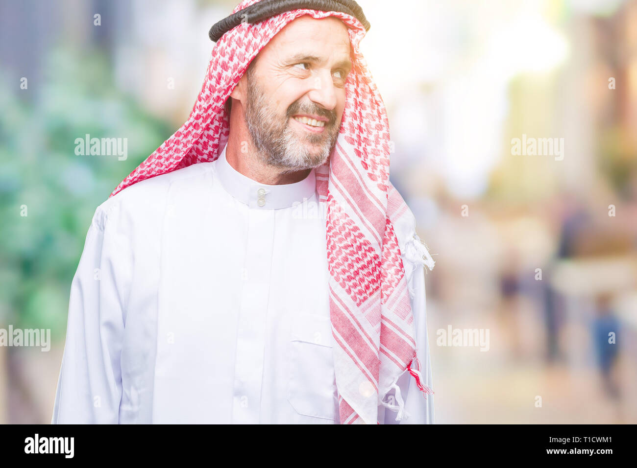 Senior uomo arabo indossando keffiyeh su sfondo isolato che guarda lontano a lato con il sorriso sul volto, espressione naturale. Ridendo fiducioso. Foto Stock