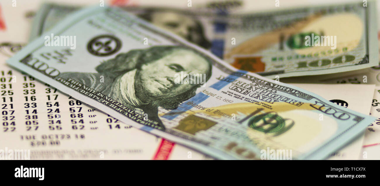 Due banconote da cento dollari al di sopra di molte le ricevute dei biglietti della lotteria. Foto Stock