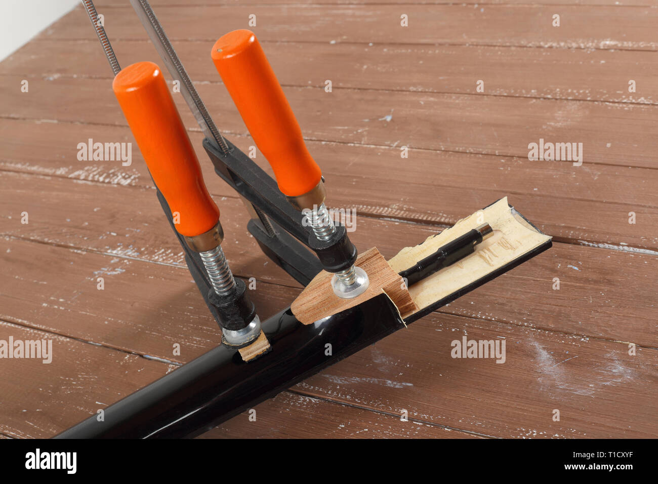 La riparazione di una chitarra e il servizio di assistenza - il serraggio di una chitarra collo sfondo di legno Foto Stock