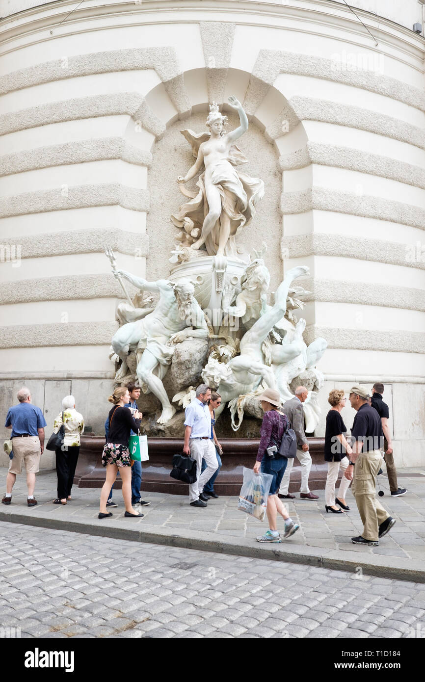 Passeggiata turistica passato il potere sul mare fontana scolpita da Rudolf Weyr sulla facciata di San Michele è ala del Palazzo di Hofburg di Vienna in Austria. Foto Stock