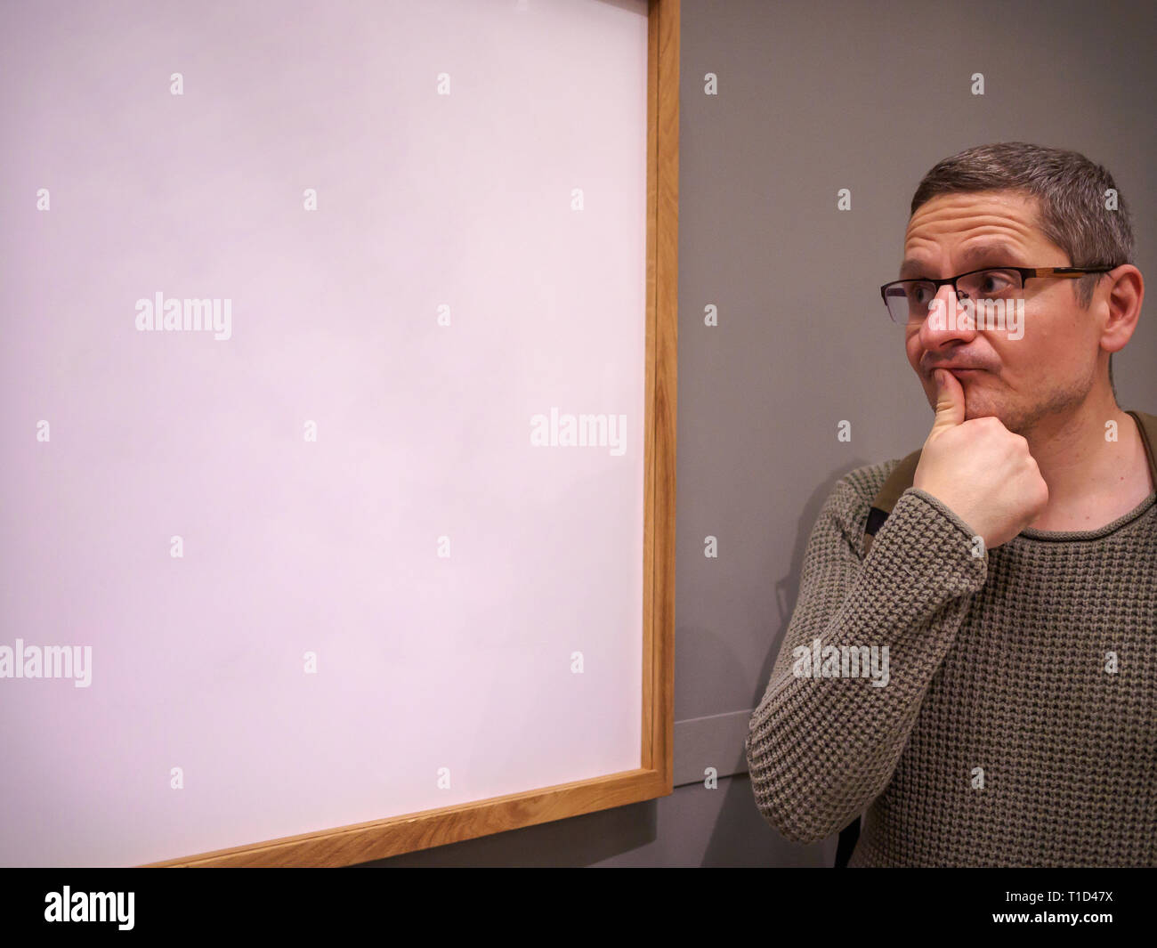 Funny Man con gli occhiali guardando attentamente in corrispondenza di un vuoto di picture frame, spazio di copia Foto Stock