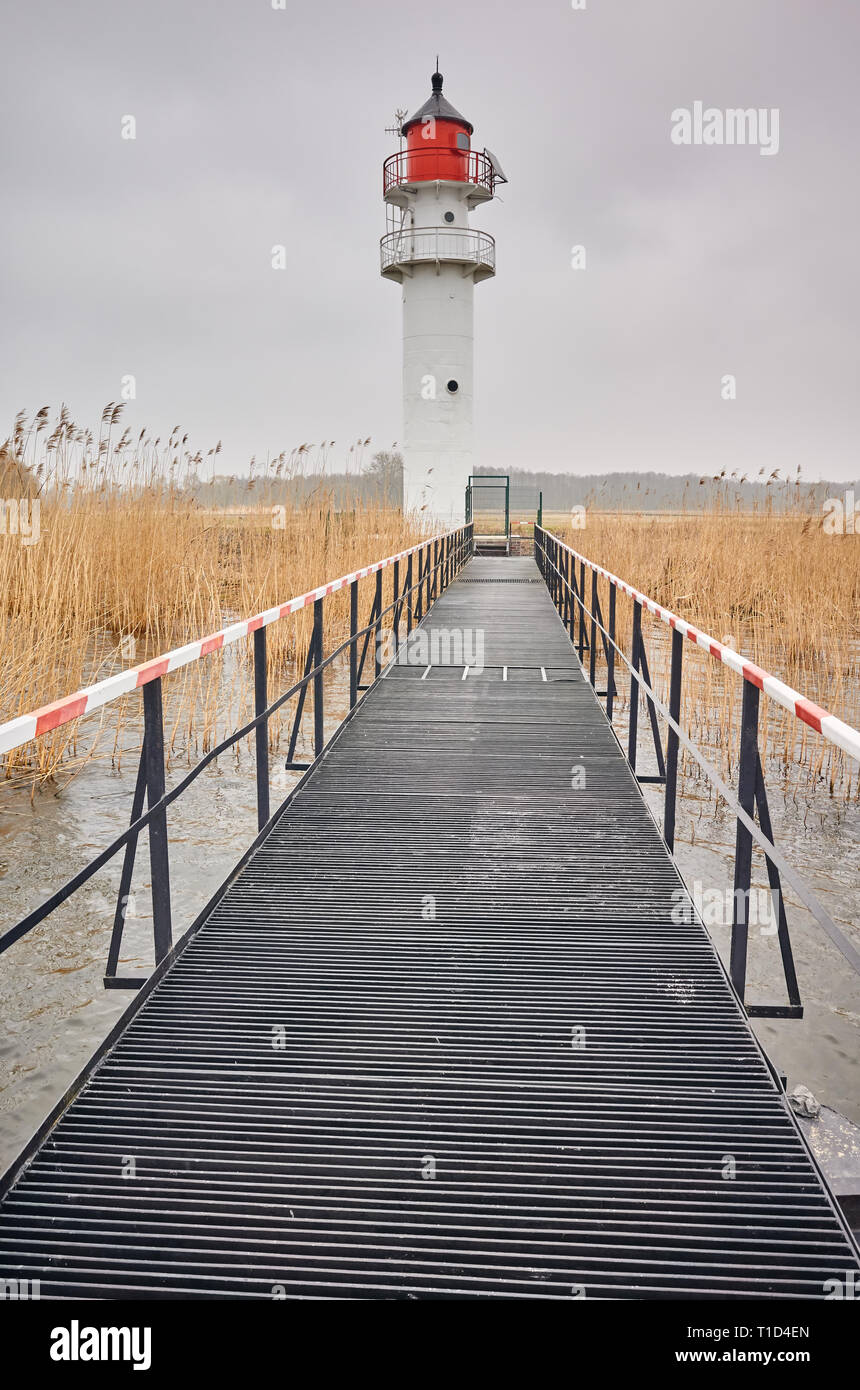 Per via navigabile faro visto da un molo di acciaio in un giorno nuvoloso. Foto Stock