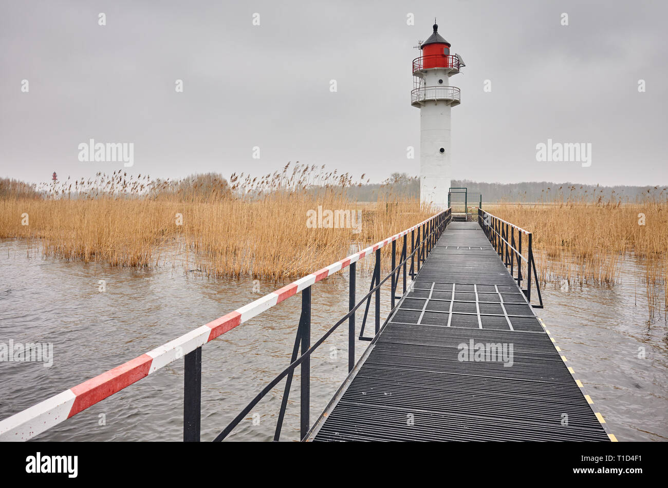 Per via navigabile faro visto da un molo di acciaio in un giorno nuvoloso. Foto Stock