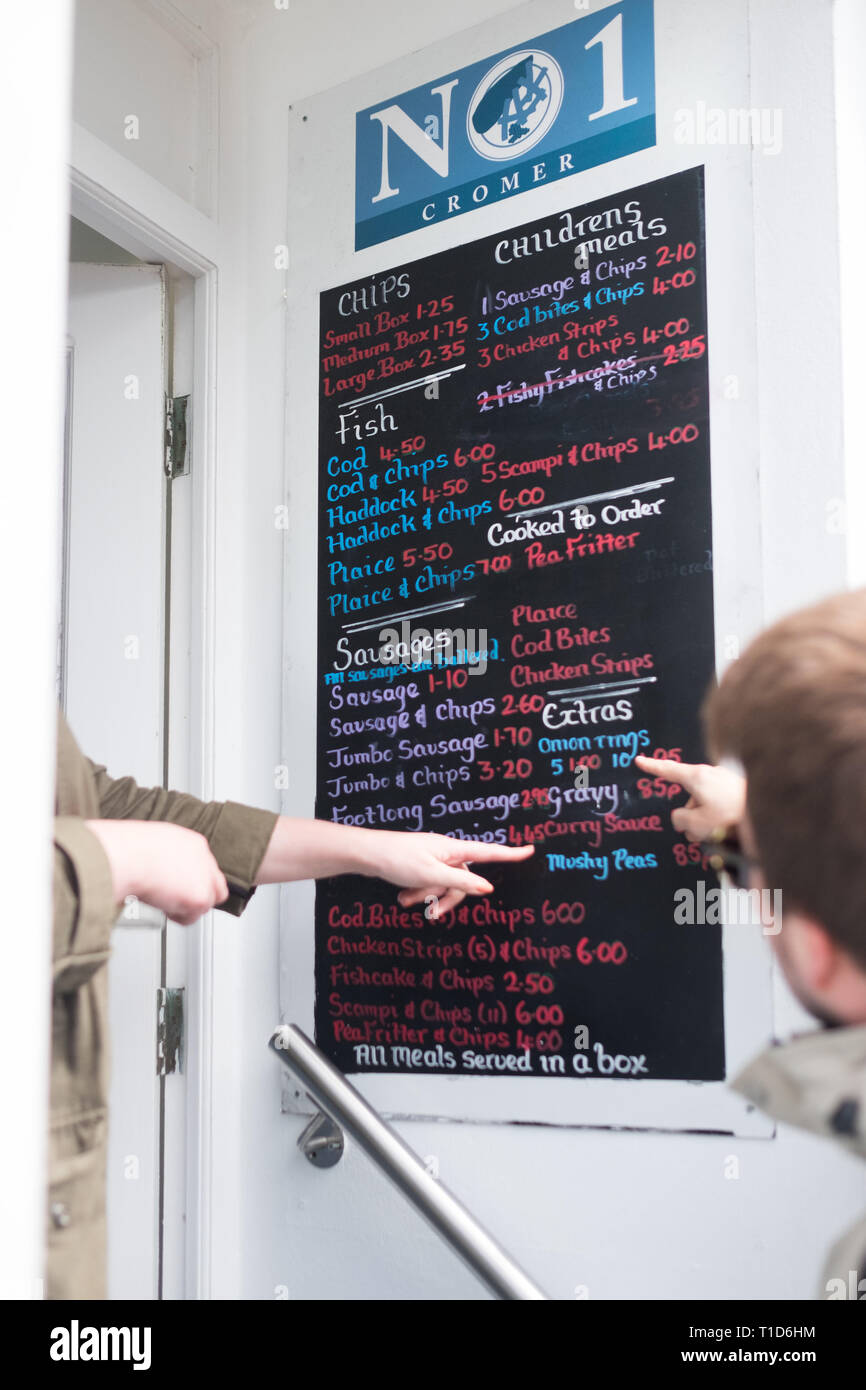 Guardando il menù a No1 Fish & Chips Shop a Cromer, North Norfolk, Inghilterra. Foto Stock