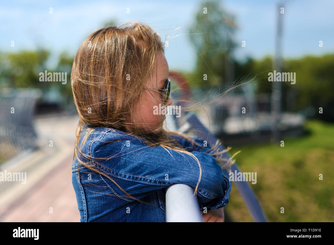 Ritratto di carino bambina indossa jeans camicia e occhiali da sole. moda, bambino modello. vista di profilo Foto Stock