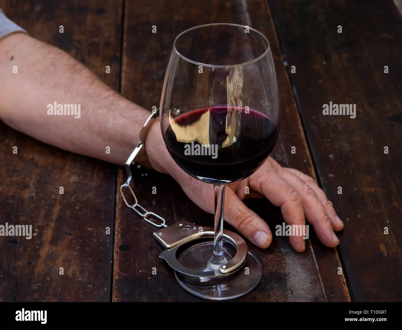 Un uomo ammanettato per un bicchiere di vino rosso. Dipendenza da alcol o  alcolismo concept Foto stock - Alamy