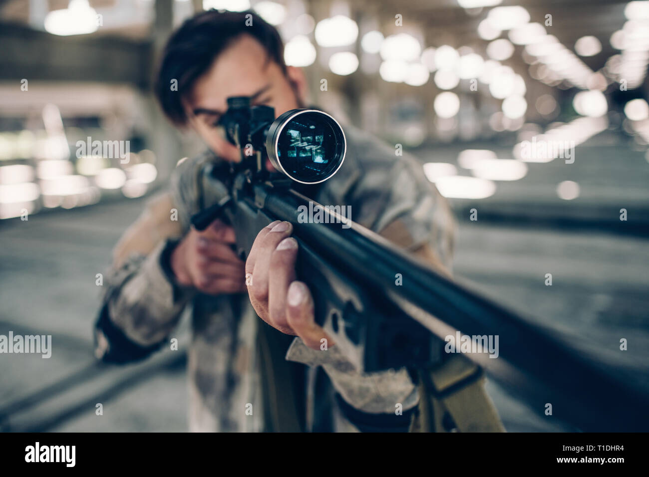 Una foto se adulto dai capelli scuri prendendo uomo obiettivo. Egli è utilizzando il paintball fucile per l. Egli è la riproduzione di gioco paintball. Foto Stock