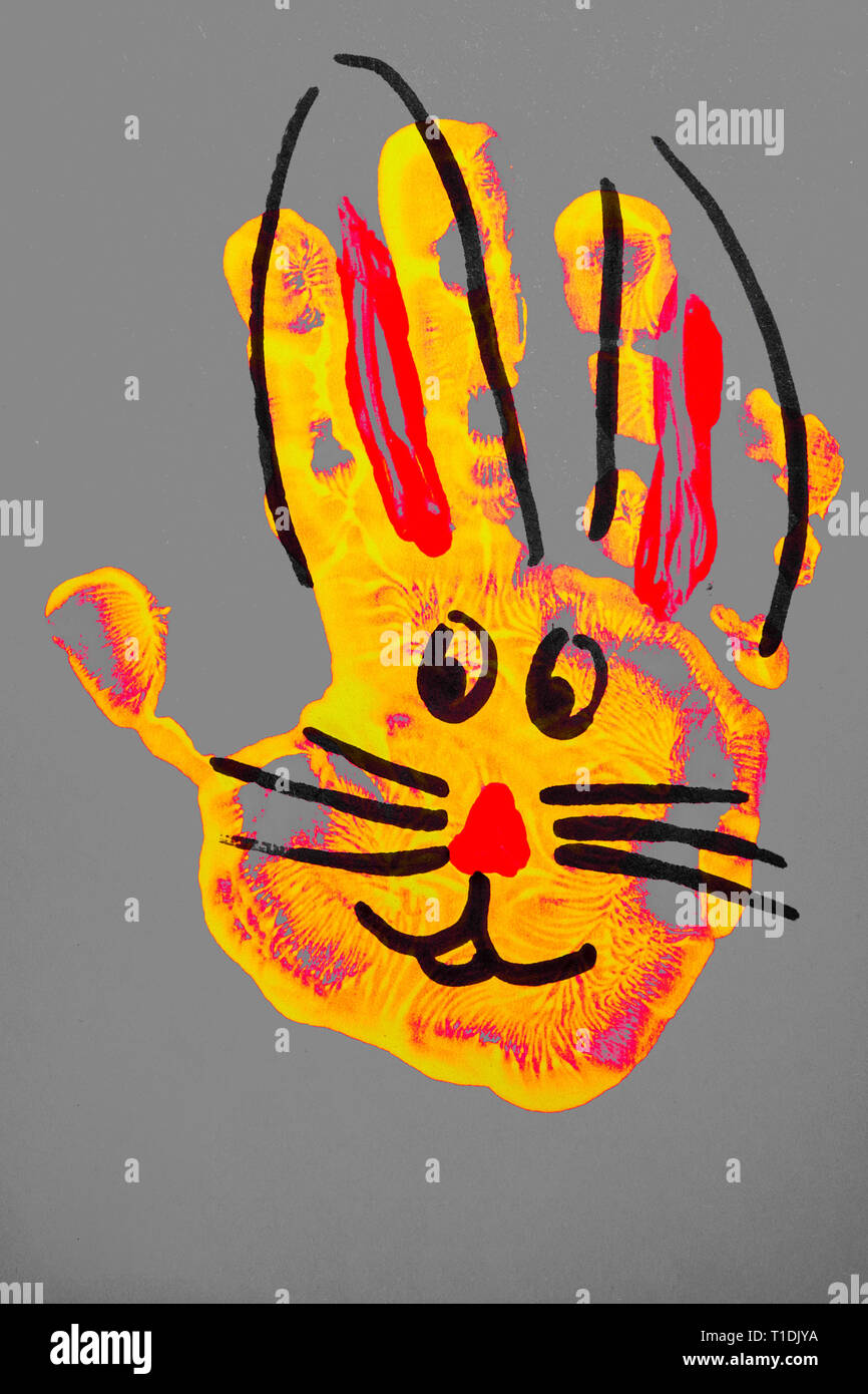 Coniglietto di pasqua dal giallo rosso ragazzi mano impronta su sfondo grigio in posizione verticale Foto Stock