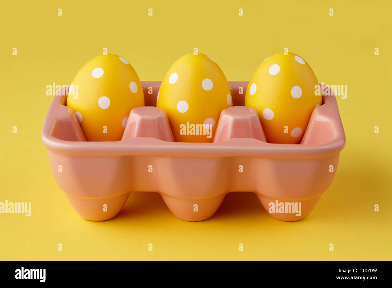 Uovo rosa con Vassoio verniciato giallo le uova di pasqua con punti su sfondo giallo, concetto di vacanza Foto Stock