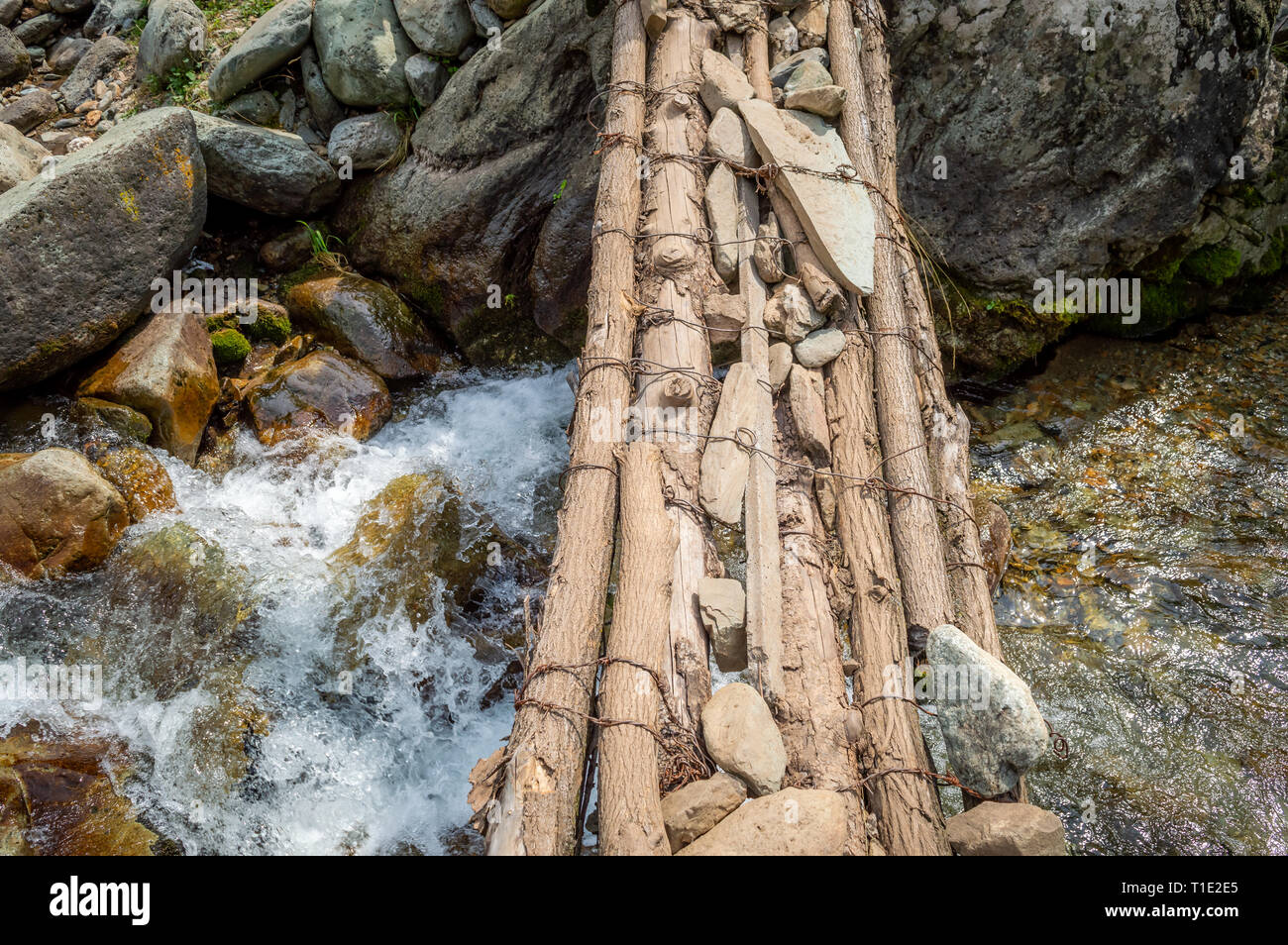 Uno stretto ponte di legno attraverso un piccolo ruscello in Kashmir Foto Stock