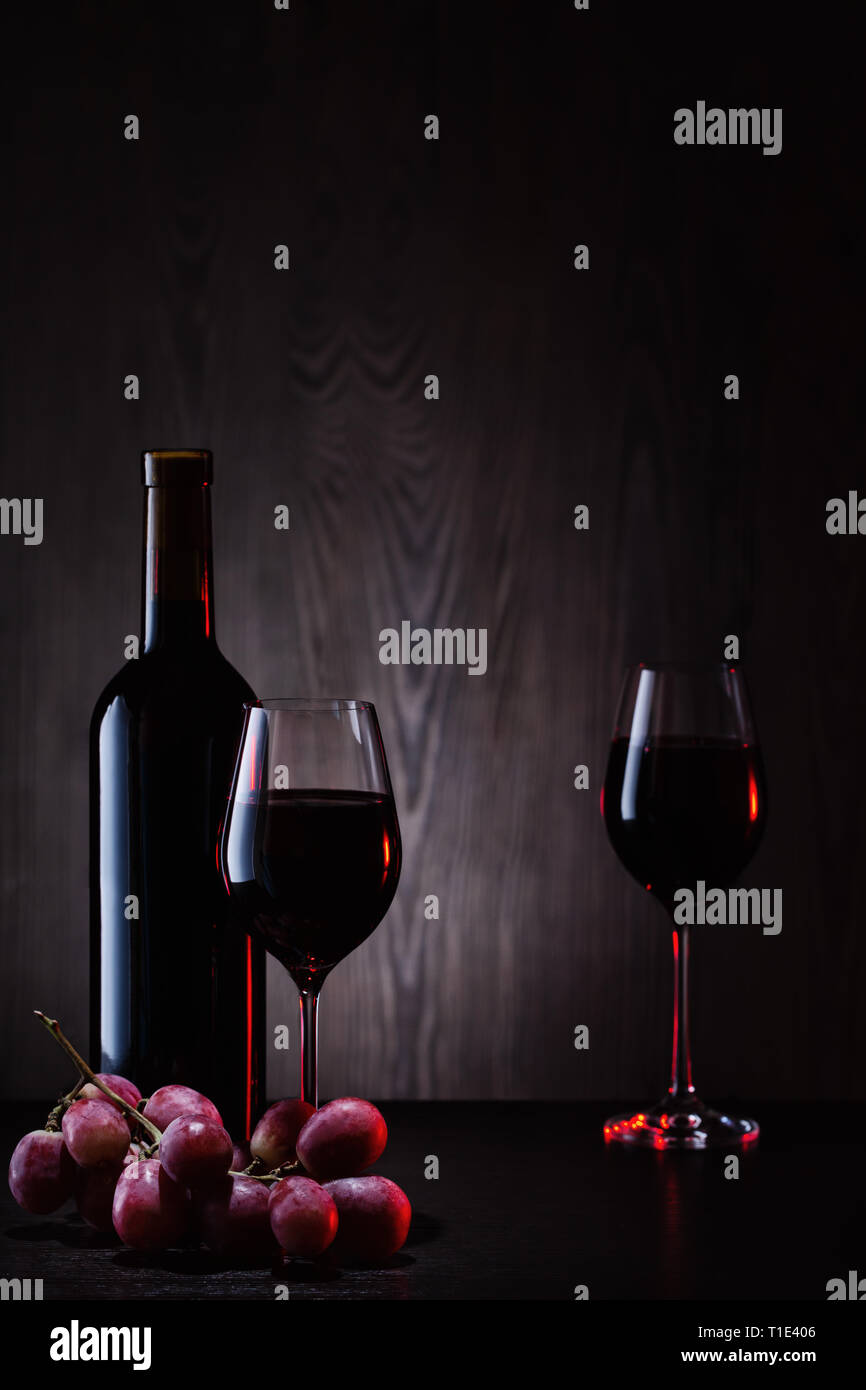 Vino rosso in bicchieri e bottiglia con grappolo di uva Foto Stock