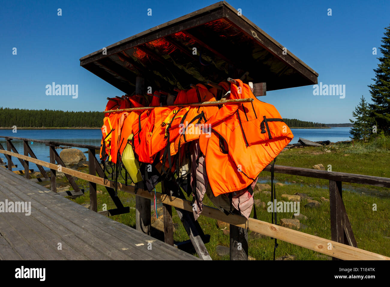 Molti orange giubbotti salvagente appeso vicino alla stazione delle barche. Foto Stock