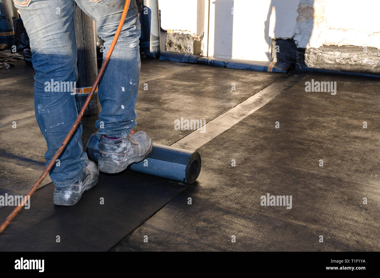 Lavori di costruzione durante i lavori di ristrutturazione di un tetto di un edificio con guaina bituminosa Foto Stock