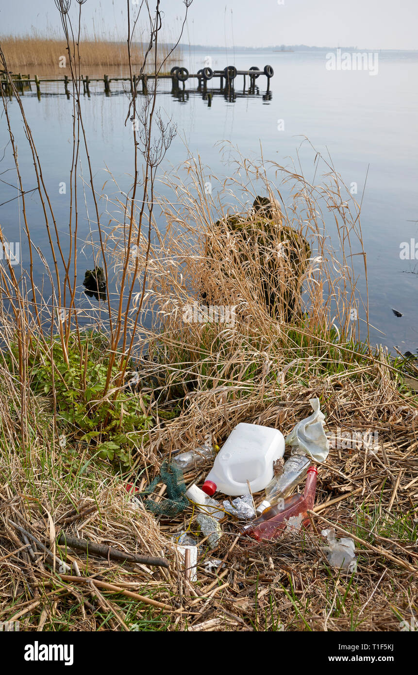 Garbage lasciata da una banca di fiume, ambiente inquinamento concetto problema immagine. Foto Stock