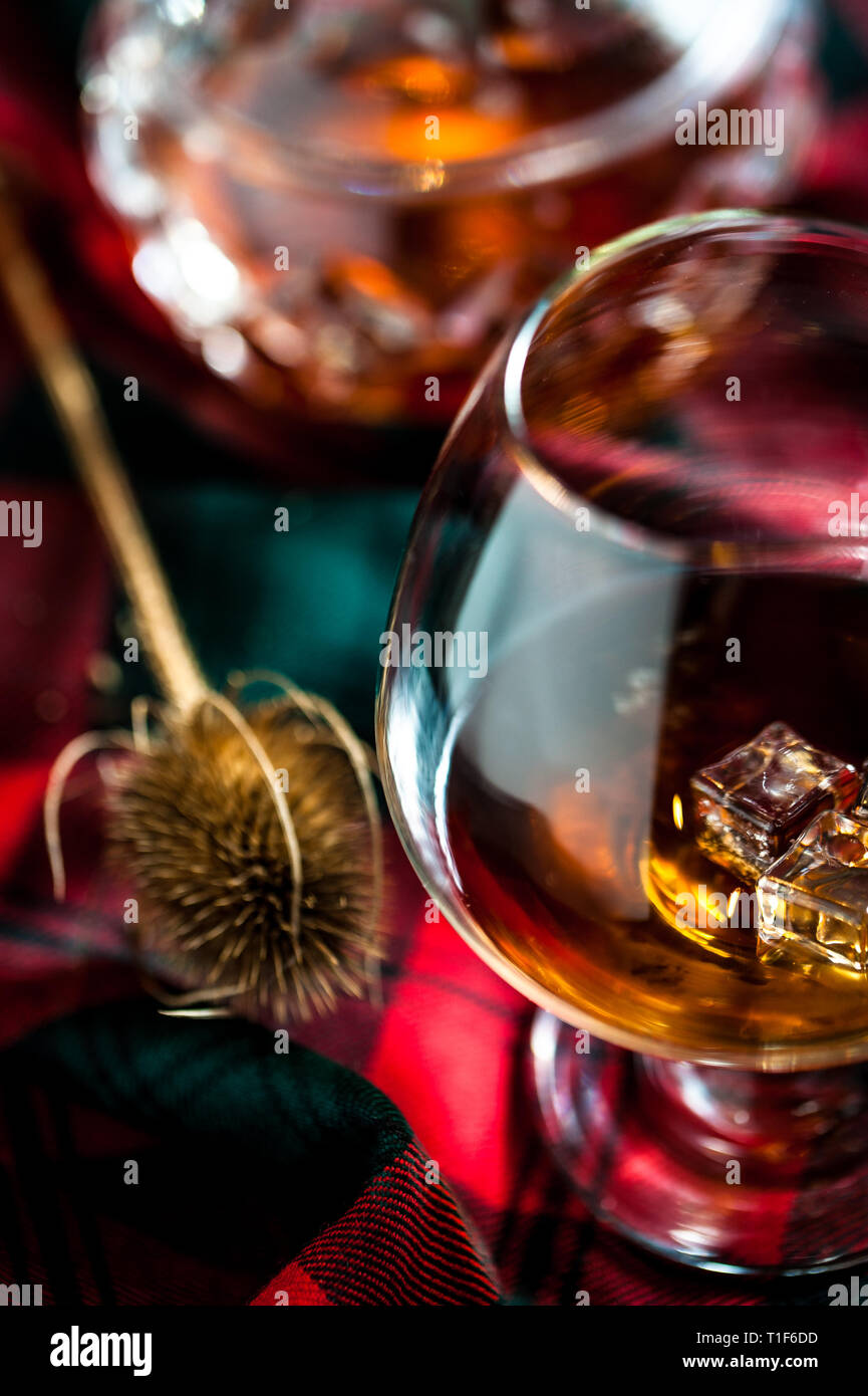 Bicchiere di whisly scozzese su una tabella con i tradizionali tartan e un thisly, simbolo della Scozia Foto Stock