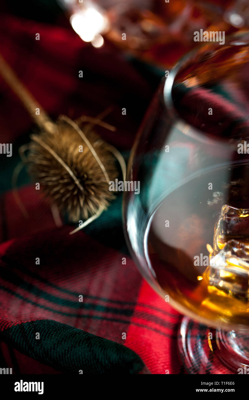 Bicchiere di whisly scozzese su una tabella con i tradizionali tartan e un thisly, simbolo della Scozia Foto Stock