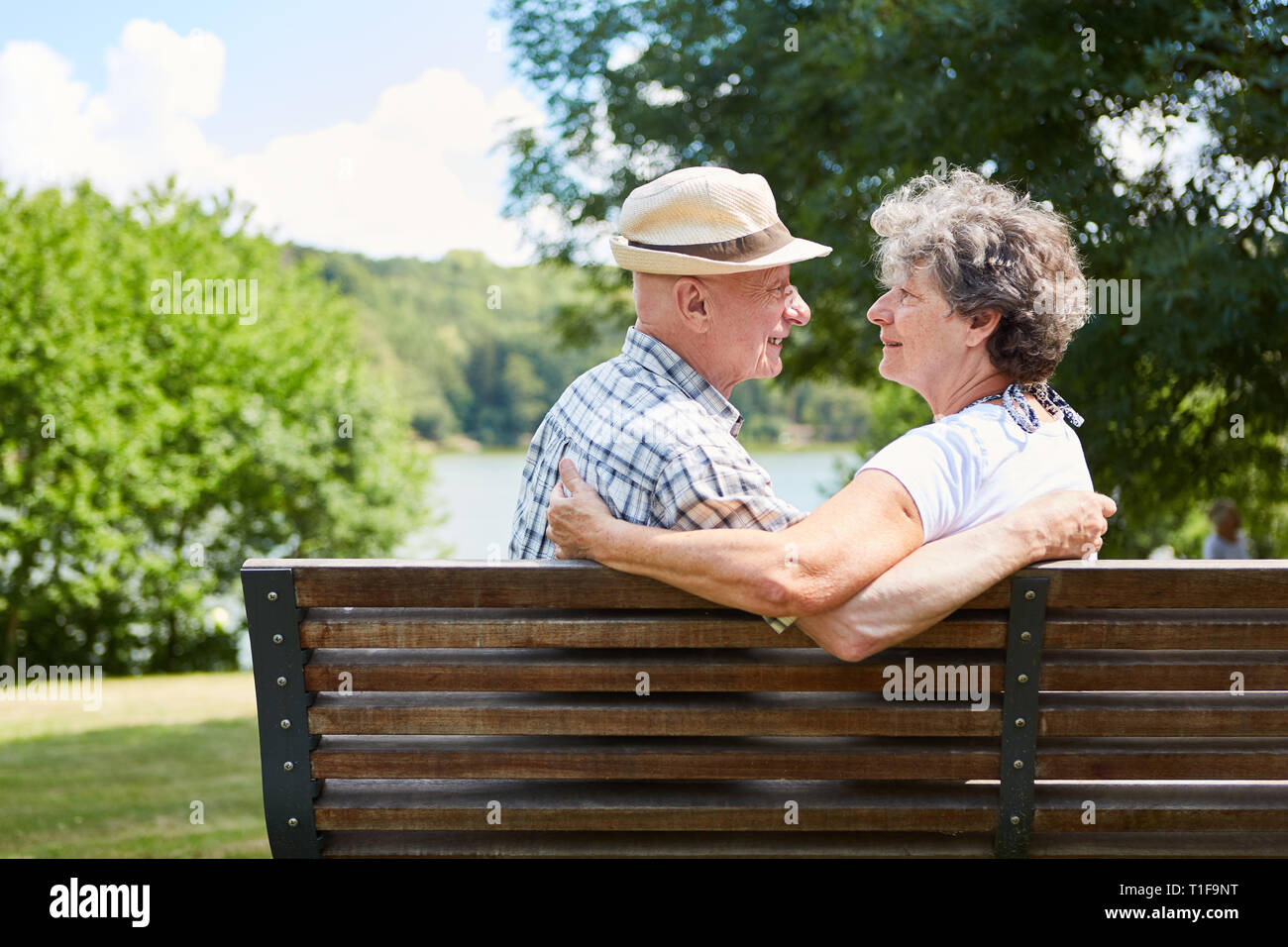 Senior amorosa giovane su una panchina nel parco in estate nella natura per conoscere ogni altro Foto Stock