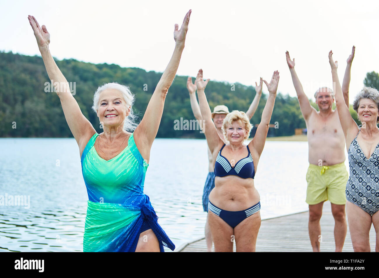 Gruppo di anziani attivi facendo indietro formazione presso il lago in vacanza estiva o rehab Foto Stock