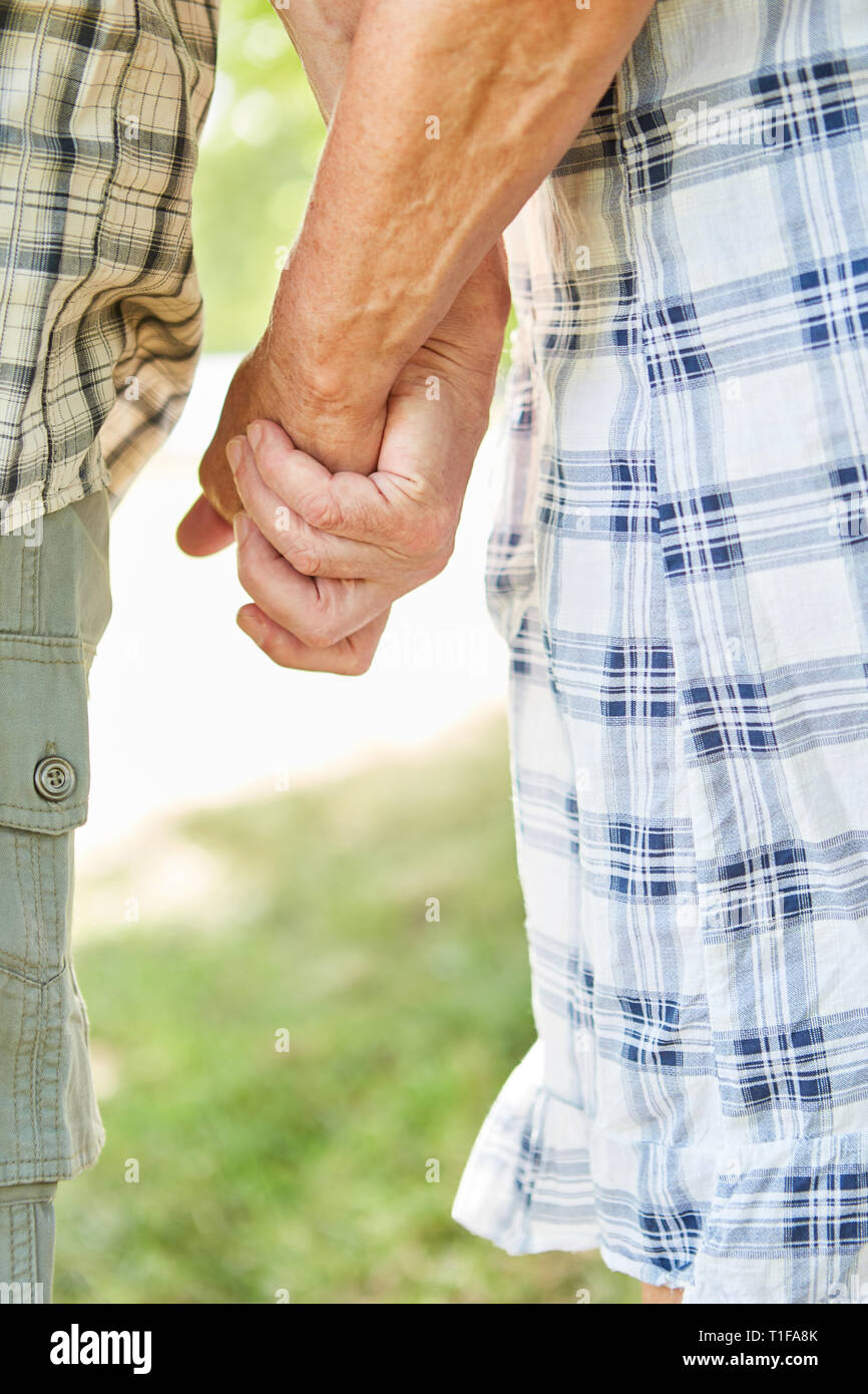 Coppia senior passeggiate mano nella mano in natura come un simbolo di amore e lealtà Foto Stock