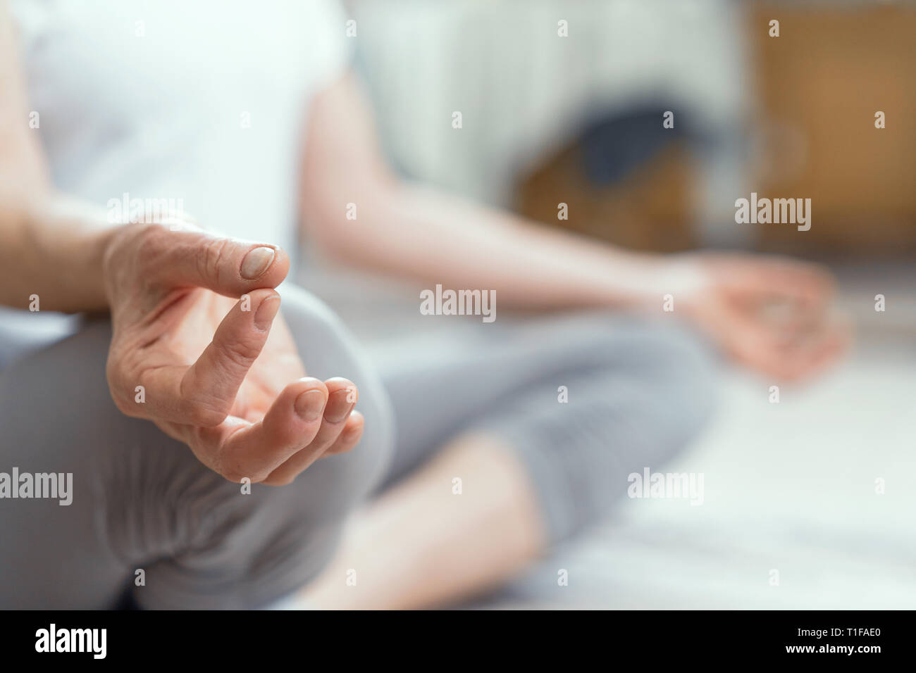 Donna matura seduta sul pavimento nella posizione del loto Foto Stock