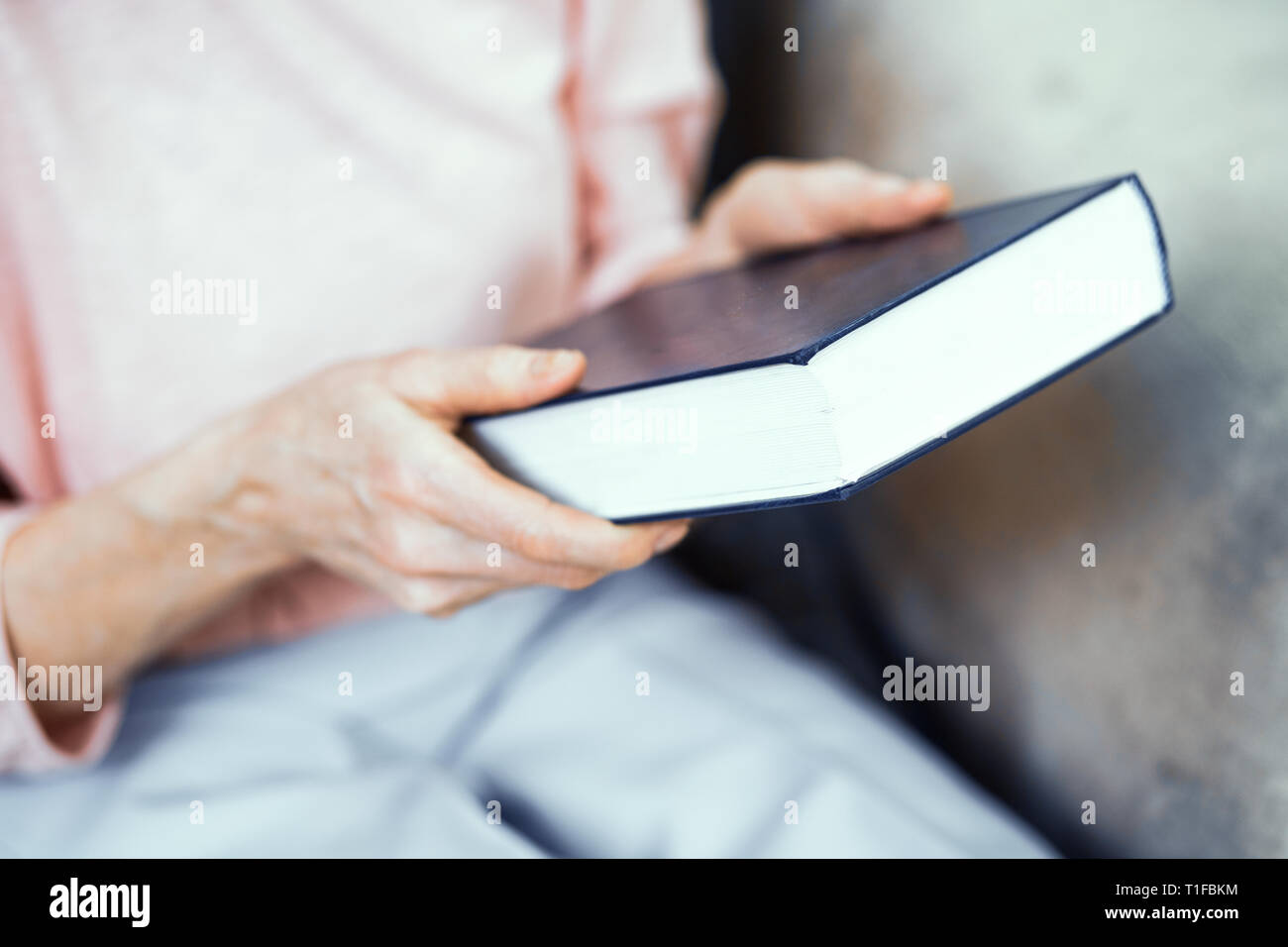 Blue spessore libro nelle mani di una donna anziana. Foto Stock