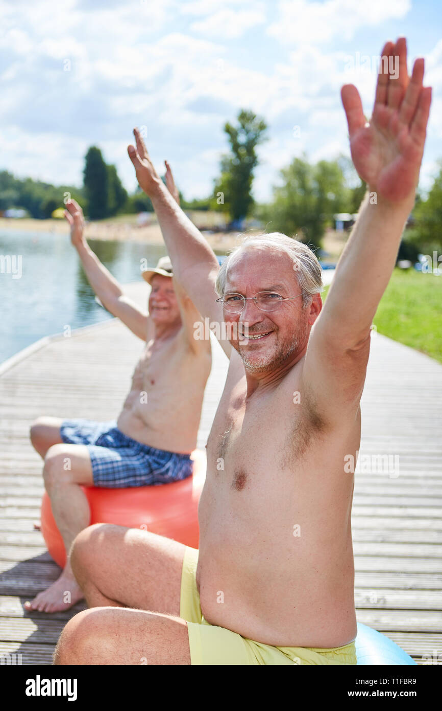 Due athletic alti uomini tendere le loro braccia durante la schiena sana formazione presso il lago Foto Stock