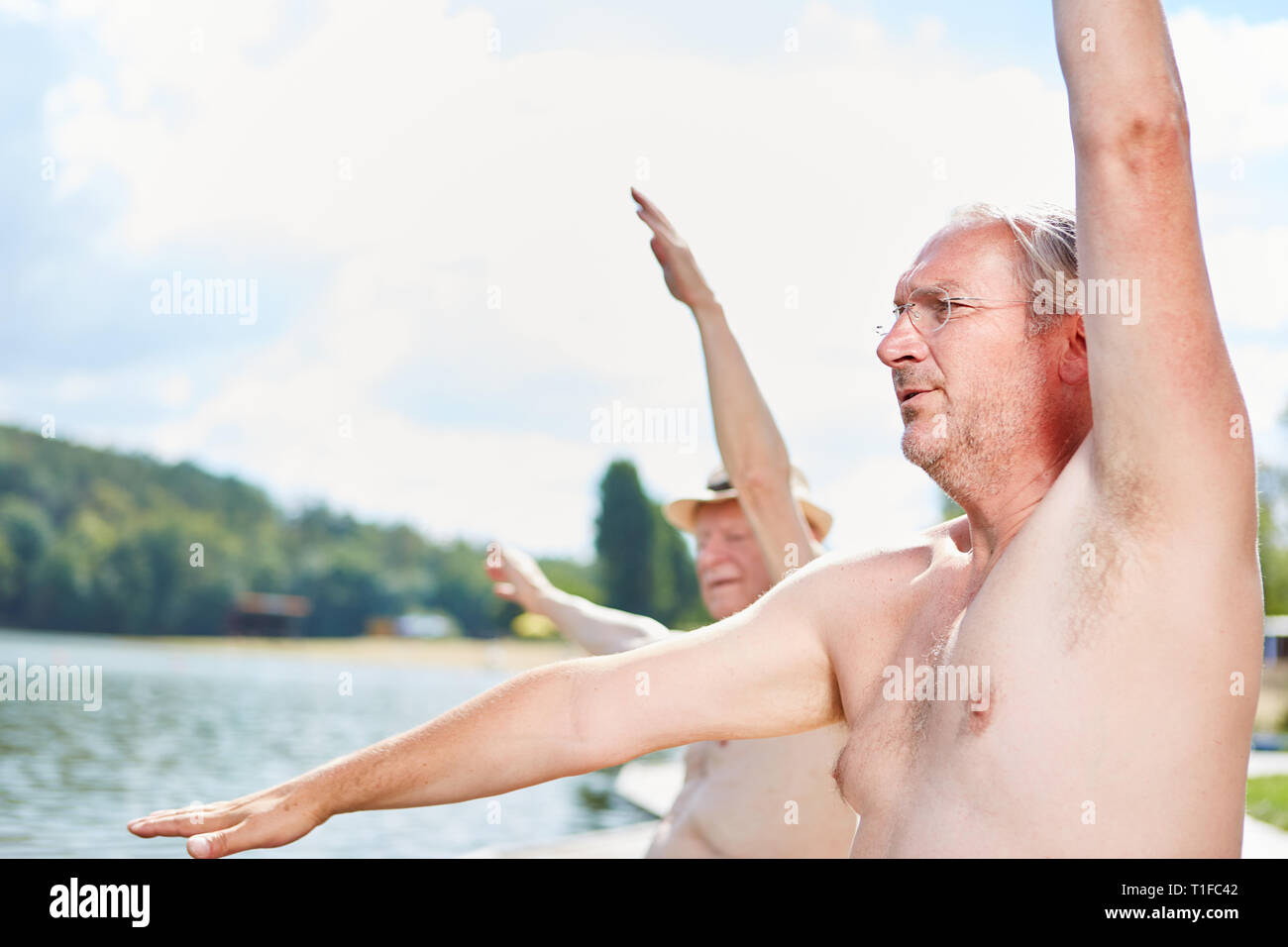 Gli anziani fare esercizi per la schiena sul lago per la loro salute e fitness Foto Stock