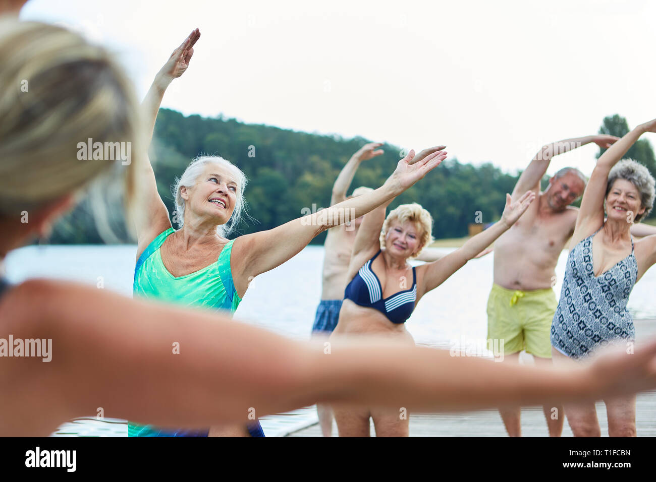 Senior group avente un sano stretching in un rehab torna in corso presso il lago in estate Foto Stock