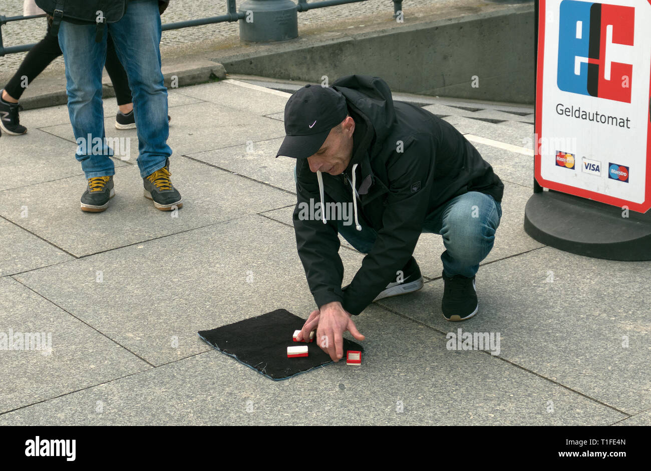 Uomo di eseguire la tazza e la sfera truffa per le strade di Berlino Germania Foto Stock